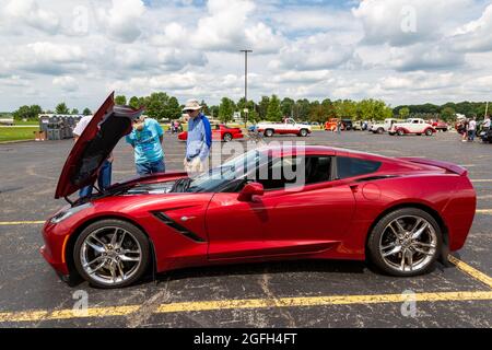 Les admirateurs inspectent une voiture de sport rouge C7 Chevrolet Corvette Stingray exposée en Angola, Indiana, États-Unis. Banque D'Images