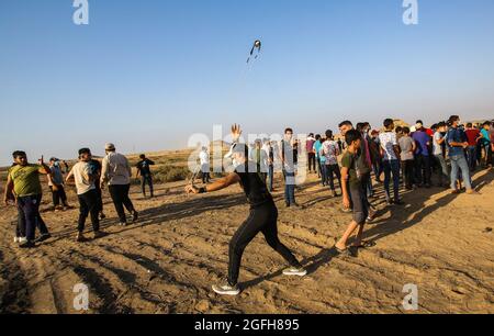 Gaza, Palestine. 25 août 2021. Un manifestant utilise un coup de feu pour lancer des pierres vers les troupes israéliennes lors de la manifestation près de la frontière entre Israël et la bande de Gaza. Des factions palestiniennes organisent une marche à la frontière entre la bande de Gaza et Israël pour protester contre la poursuite du siège dans la bande de Gaza et le retard de reconstruction, Selon les médecins palestiniens, quatorze Palestiniens ont été blessés lors des affrontements près de la frontière à l'est de Khan Younis, dans le sud de la bande de Gaza. (Photo par Ahmed Zakot/SOPA Images/Sipa USA) crédit: SIPA USA/Alay Live News Banque D'Images