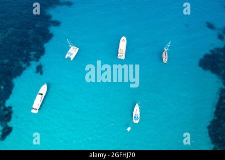 Vue d'en haut, vue aérienne stupéfiante de certains bateaux flottant sur une eau turquoise et cristalline pendant une journée ensoleillée. Costa Smeralda, Sardaigne, Italie. Banque D'Images