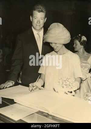 La mariée met sa signature sur le livre des mariages, Italie des années 60 Banque D'Images