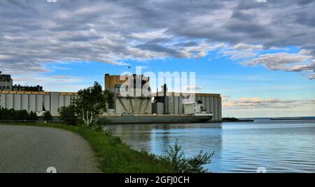 Un élévateur de grain centenaire se trouve sur le lac supérieur à Thunder Bay, Ontario, Canada, alors qu'un cargo arrive pour ramasser le grain le jour du printemps. Banque D'Images