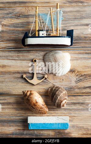 Coquillages, ancre en bois et bateau jouet sur fond de merde Banque D'Images