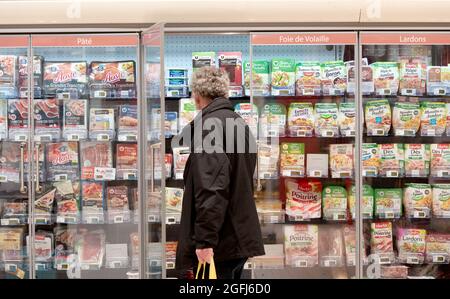 Supermarché Super U: Un homme au milieu du rayon des aliments frais, emballé sous vide de viande froide cuite, protége, foie de volaille, dés de bacon Banque D'Images