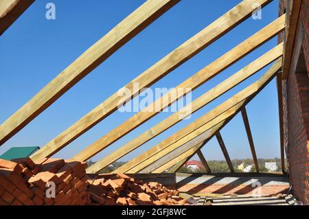 Un gros plan sur l'encadrement du toit d'une maison en brique avec des fermes, des poutres de toit, des avant-toits de toit, des accolades et des planches dans la construction de toiture. Banque D'Images