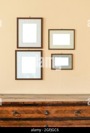 Quatre cadres photo vides de différentes tailles affichés sur un mur au-dessus d'un panneau latéral en bois prêt pour le placement de vos œuvres d'art ou de vos photos Banque D'Images