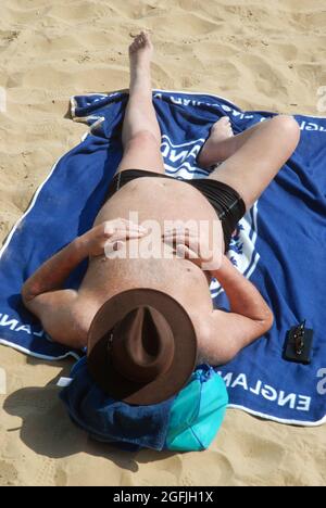 Vieil homme allongé sur la plage, Cleethorpes, North East Lincolnshire, Angleterre. Banque D'Images