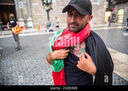 Barcelone, Espagne. Août 25 2021: Un manifestant couvert d'un drapeau afghan est vu montrant un tatouage de la carte afghane avec les couleurs du drapeau afghan devant la Generalitat de Catalunya. L'association afghane de Barcelone a manifesté devant la Generalitat de Catalogne pour demander au gouvernement la protection et l'évacuation de leurs familles qui sont restées en Afghanistan. Crédit : DAX Images/Alamy Live News Banque D'Images