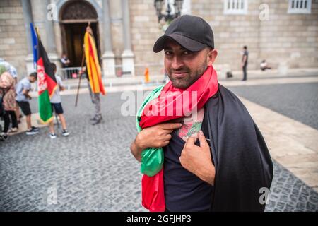 Barcelone, Espagne. Août 25 2021: Un manifestant couvert d'un drapeau afghan est vu montrant un tatouage de la carte afghane avec les couleurs du drapeau afghan devant la Generalitat de Catalunya. L'association afghane de Barcelone a manifesté devant la Generalitat de Catalogne pour demander au gouvernement la protection et l'évacuation de leurs familles qui sont restées en Afghanistan. Crédit : DAX Images/Alamy Live News Banque D'Images