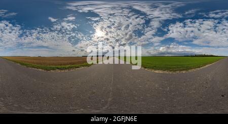 360 vue panoramique hdri sur l'ancienne route asphaltée entre les champs en soirée d'été avec des nuages impressionnants en projection sphérique équirectangulaire, prêt pour VR A Banque D'Images