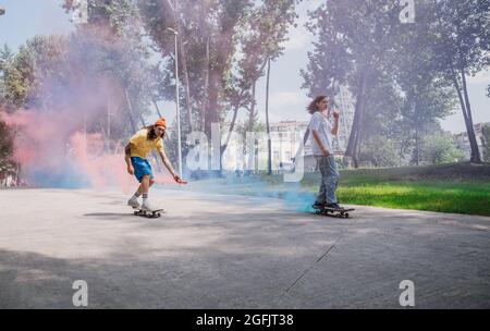 patineurs avec des bombes de fumée colorées. Skateboarders professionnels qui s'amusent au skate Park Banque D'Images