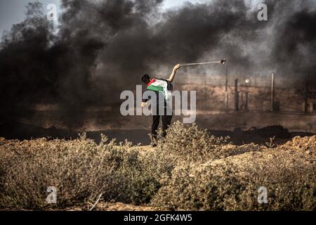 Gaza, Palestine. 25 août 2021. Un manifestant palestinien utilise un coup de feu pour lancer des pierres sur l'armée israélienne lors d'une manifestation près de la frontière entre Israël et la bande de Gaza. Une marche a été organisée par les factions palestiniennes à la frontière entre la bande de Gaza et Israël pour protester contre la poursuite du siège imposé à la bande de Gaza et à Israël. L'entrée de matériaux de construction dans la bande de Gaza a été retardée pour rebâtir les vestiges de la dernière agression en mai dernier. (Photo de Yousef Masoud/SOPA Images/Sipa USA) crédit: SIPA USA/Alay Live News Banque D'Images