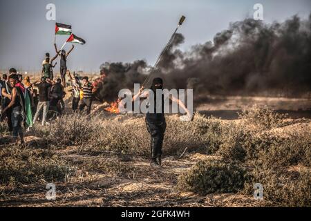 Gaza, Palestine. 25 août 2021. Un manifestant palestinien utilise un coup de feu pour lancer des pierres sur l'armée israélienne lors d'une manifestation près de la frontière entre Israël et la bande de Gaza. Une marche a été organisée par les factions palestiniennes à la frontière entre la bande de Gaza et Israël pour protester contre la poursuite du siège imposé à la bande de Gaza et à Israël. L'entrée de matériaux de construction dans la bande de Gaza a été retardée pour rebâtir les vestiges de la dernière agression en mai dernier. (Photo de Yousef Masoud/SOPA Images/Sipa USA) crédit: SIPA USA/Alay Live News Banque D'Images