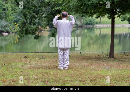 À la fin d'un entraînement de Tai Chi un homme d'âge moyen semble prier ou bénir la région environnante. À Queens, New York. Banque D'Images