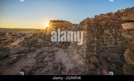 Vieux mur au sommet d'une montagne rocheuse au coucher du soleil à Taghit, en Algérie Banque D'Images