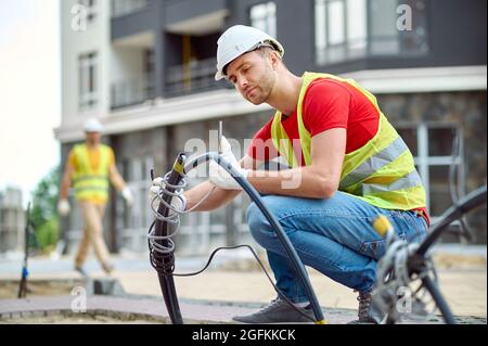 Ouvrier de construction concentré et qualifié en gants de coton installant de l'électricité Banque D'Images