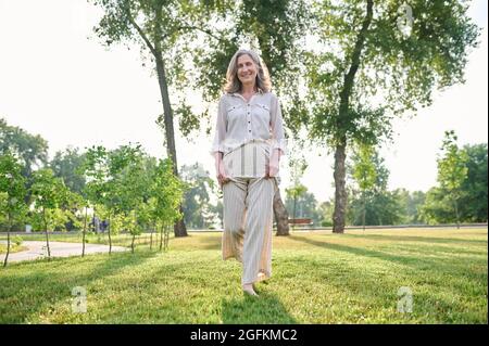 Femme marchant pieds nus sur l'herbe dans le parc Banque D'Images