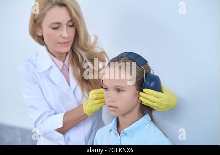 Audiologiste spécialisé préparant un jeune patient à un test d'audiométrie Banque D'Images