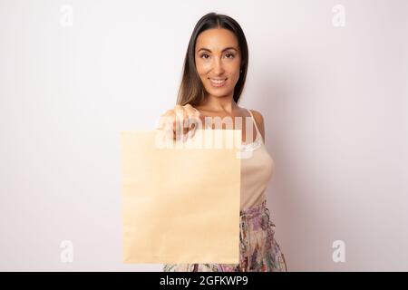 Une jeune jolie fille en vêtements décontractés sur fond blanc avec un sac en papier dans ses mains. Banque D'Images