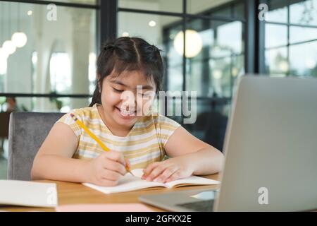 Mignonne et heureuse petite fille enfants utilisant un ordinateur portable, étudiant par le biais du système d'e-learning en ligne. Banque D'Images