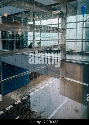 Deux employés d'aéroport s'assoient dans un aéroport vide derrière un mur de verre Banque D'Images