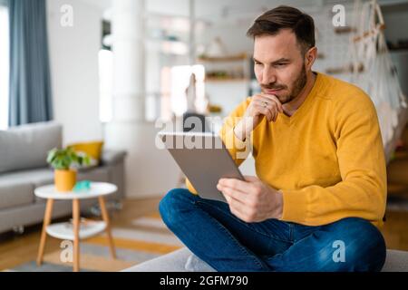 Portrait d'un beau jeune homme heureux à l'aide d'une tablette numérique Banque D'Images