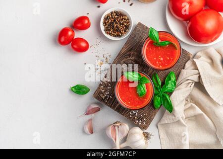 Deux verres de jus de tomate sur fond gris avec ingrédients. Boissons saines. Vue de dessus. Banque D'Images