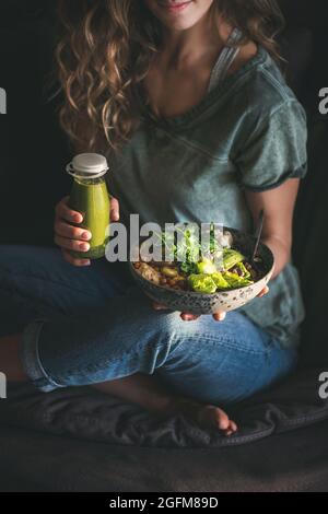 Femme assise et tenant un super-bol et un smoothie sains Banque D'Images