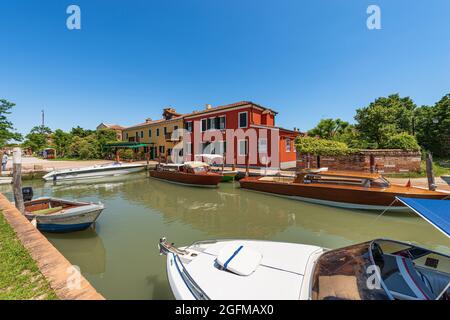 Port de l'île de Torcello avec de nombreux bateaux rapides et deux bateaux-taxis traditionnels faits de bois amarré. Lagon vénitien, Venise, Italie, Europe. Banque D'Images