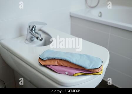 quelques serviettes en tissu de différentes couleurs sur la couverture d'un bidet blanc dans une salle de bains moderne Banque D'Images