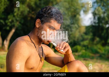 Un jeune homme afro-américain vaporisant de l'e-cigarette à l'aide d'e-liquide Banque D'Images