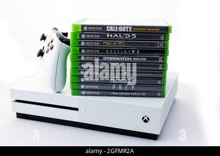 Suffolk, Royaume-Uni juin 01 2020: Une console de jeu Microsoft Xbox One S avec une manette sans fil et une pile de jeux tournés sur un fond blanc Uni Banque D'Images
