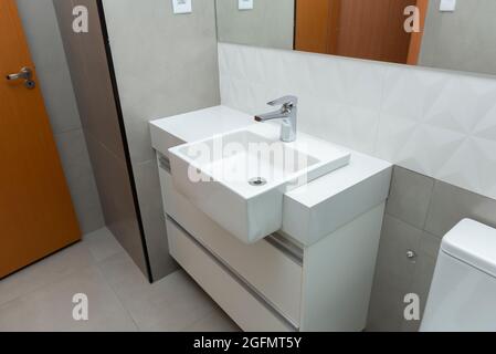 Lavabo rectangulaire en marbre blanc avec lavabo moderne superposé et robinet en acier inoxydable brillant sur mobilier personnalisé dans la salle de bains. Mur décoré avec relief Banque D'Images