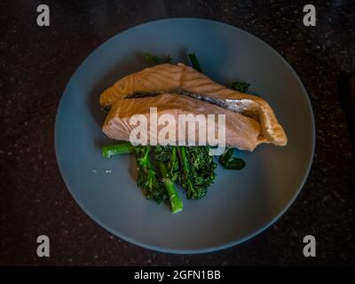 Gros plan de saumon et de brocoli cuits à la vapeur sur une assiette bleue Banque D'Images