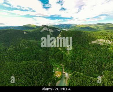 Vue panoramique sur un lac dans les montagnes entourées d'une forêt de pins verts. Photo prise à partir d'un drone à une altitude plus élevée avec l'appareil photo orienté vers le bas. Banque D'Images