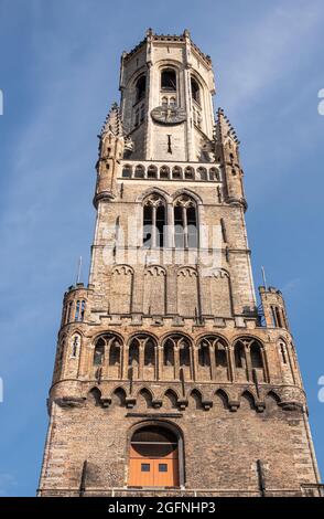 Brugge, Flandre, Belgique - 4 août 2021 : gros plan de la moitié supérieure en brique brune de Halletoren dans le cadre du beffroi contre le ciel bleu. Banque D'Images