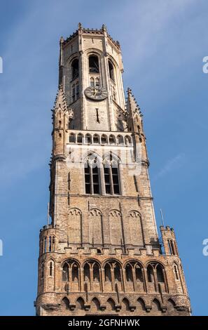 Brugge, Flandre, Belgique - 4 août 2021 : partie supérieure en brique brune de Halletoren faisant partie du beffroi contre le ciel bleu. Banque D'Images