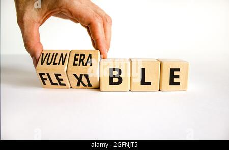 Symbole vulnérable ou flexible. Homme d'affaires transforme les cubes en bois et les mots « vulnérable » en « flexible ». Magnifique arrière-plan blanc, espace de copie. Unité commerciale Banque D'Images
