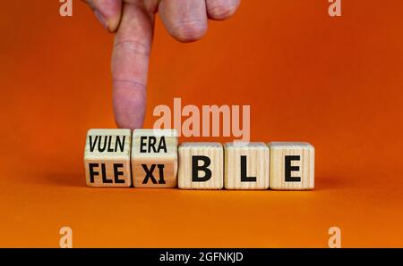 Symbole vulnérable ou flexible. Homme d'affaires transforme les cubes en bois et les mots « vulnérable » en « flexible ». Magnifique arrière-plan orange, espace de copie. B Banque D'Images