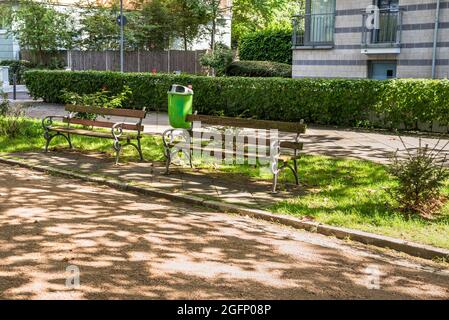 Bancs en bois vides le long d'une rue piétonne au bord de la rivière, par une journée ensoleillée d'été.Les immeubles d'appartements sont en arrière-plan. Banque D'Images