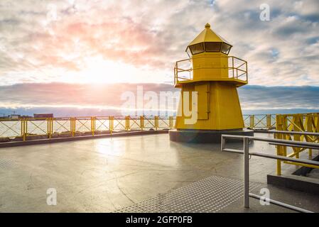 Phare en acier jaune sous ciel nuageux au coucher du soleil Banque D'Images