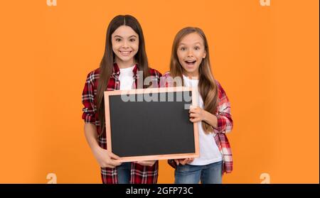 les filles de l'adolescence heureux tiennent le tableau noir. publicité des enfants. retour à l'école. enfants présentant l'information Banque D'Images