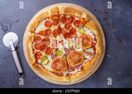 Pizza au pepperoni et pizza à la saucisse sur la même planche. Dans un couteau à pizza Banque D'Images