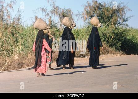 Louxor, Égypte, décembre 1967.. Femmes portant des cruches d'eau sur la tête. Banque D'Images