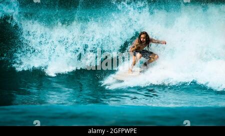 Un homme local aux cheveux longs surfant sur une vague d'éclaboussures sur la côte du Pacifique du Costa Rica, en Amérique centrale Banque D'Images