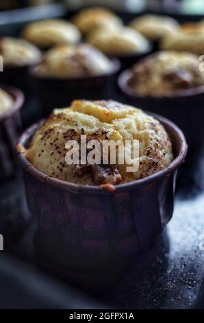 Muffin à la vanille et poussière de chocolat sous de petites formes brunes, cuisine maison Banque D'Images