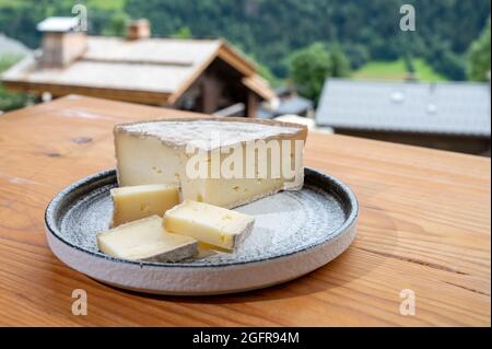 Collection de fromages, tomme de savoie et village de montagnes françaises en haute-Savoie en été en arrière-plan Banque D'Images