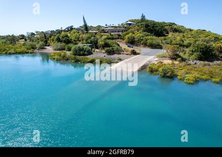 Drone vers une rampe d'accès dans une petite communauté côtière sur la marée entrante avec de l'eau turquoise Banque D'Images