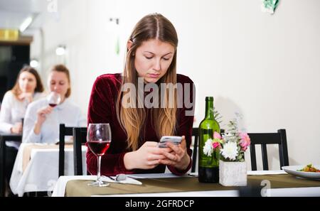 Femme élégante en colère s'attend à ce que l'homme pour le dîner dans le restaurant de luxe Banque D'Images