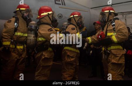 210824-N-UF592-2027 MER D'ARABIE (AOÛT 24, 2021) – les marins se préparent à combattre un incendie simulé au cours d'un exercice de quartier général dans la baie hangar du porte-avions USS Ronald Reagan (CVN 76) dans la mer d'Arabie, août 24. Ronald Reagan est le navire amiral du Carrier Strike Group 5 et est déployé dans la zone d'opérations de la 5e flotte des États-Unis à l'appui des opérations navales afin d'assurer la stabilité et la sécurité maritimes dans la région centrale, Reliant la Méditerranée et le Pacifique à travers l'ouest de l'océan Indien et trois points d'étranglement stratégiques. (É.-U. Photo de la marine par le Matelot de 1re classe Eri Banque D'Images