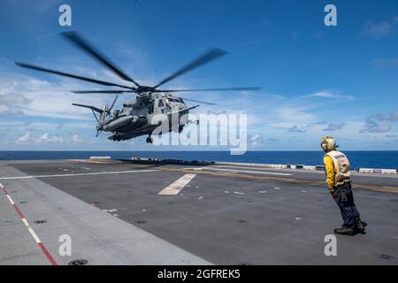 MER DES PHILIPPINES (août 25, 2021) Aviation Boatswain’s Mate (Handling) 3rd Class Steven Crisologo, de Manille (Philippines), affecté au navire d’assaut amphibie déployé vers l’avant USS America (LHA 6), signale un hélicoptère CH-53E Super Stallion de la 31e unité expéditionnaire maritime (MEU) pour atterrir sur le pont de vol du navire pendant les opérations de vol. L'Amérique et le 31e élément de combat aérien du MEU maintiennent une plate-forme stratégique prête pour une variété de missions. L'Amérique, vaisseau amiral de l'America Expeditionary Strike Group, ainsi que le 31e MEU, opère dans la zone de la 7e flotte des États-Unis dont la responsabilité est de Banque D'Images